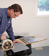 installing a waterproof vapor barrier on a basement floor to prepare for basement carpeting in a Brainerd home