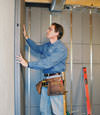 Insulated basement wall panels being placed against a concrete foundation wall in Rice Lake